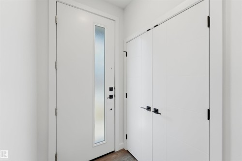 Entryway featuring a white door with an opaque glass insert, modern black hardware, and wood-finish flooring - 12447 47 Street, Edmonton, AB - Indoor Photo Showing Other Room