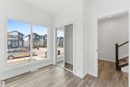 Room featuring a large window, light wood-finish flooring, white baseboards, and a closet with mirrored sliding doors - 12447 47 Street, Edmonton, AB - Indoor Photo Showing Other Room
