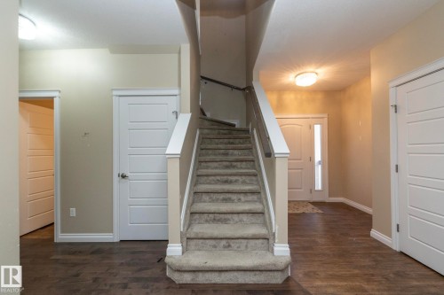 Carpeted staircase with white trim and dark wood handrail - 151 Caledonia Drive, Leduc, AB - Indoor Photo Showing Other Room