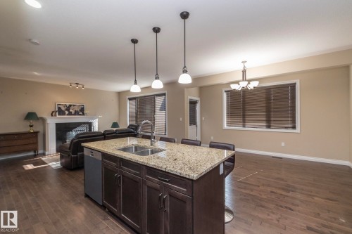 Open-concept living space featuring a central kitchen island with a double basin sink and granite countertop - 151 Caledonia Drive, Leduc, AB - Indoor Photo Showing Kitchen With Double Sink