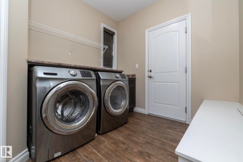 Dedicated laundry area featuring wood-finish flooring and neutral wall tones - 151 Caledonia Drive, Leduc, AB - Indoor Photo Showing Laundry Room