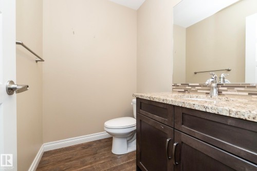 Bathroom featuring a dark wood-finish vanity with a light speckled countertop, chrome faucet, and a decorative tile backsplash - 151 Caledonia Drive, Leduc, AB - Indoor Photo Showing Bathroom