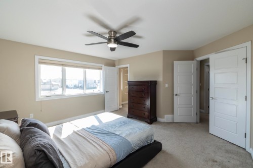 Carpeted room featuring a ceiling fan with integrated lighting, a large window with blinds, and multiple paneled doors - 151 Caledonia Drive, Leduc, AB - Indoor Photo Showing Bedroom