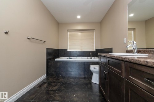 Bathroom featuring a dark wood-finish vanity with a single basin sink, a brown-flecked countertop, and a large wall-mounted mirror - 151 Caledonia Drive, Leduc, AB - Indoor Photo Showing Bathroom