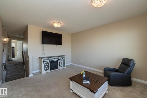Carpeted room with neutral wall tones and two ornate semi-flush mount light fixtures - 151 Caledonia Drive, Leduc, AB - Indoor Photo Showing Living Room