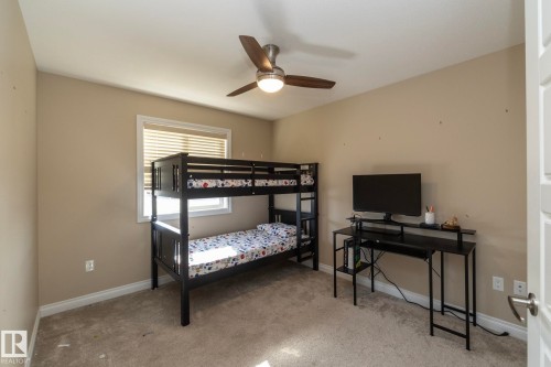 Carpeted room with a window featuring horizontal blinds, neutral wall paint, and a ceiling fan with integrated lighting - 151 Caledonia Drive, Leduc, AB - Indoor Photo Showing Bedroom