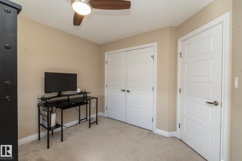 Neutral-toned room featuring a ceiling fan with light, plush carpet, and two modern white doors with horizontal paneling - 151 Caledonia Drive, Leduc, AB - Indoor