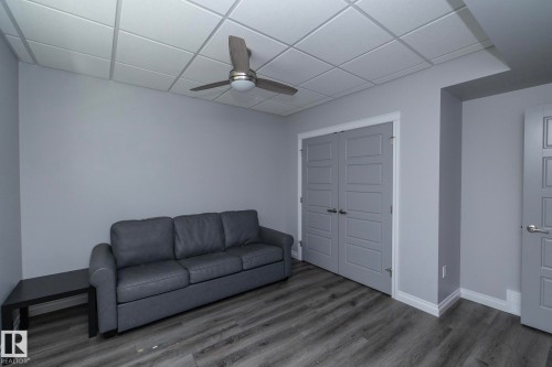 Room featuring wood-finish flooring, a ceiling fan, and drop ceiling panels - 151 Caledonia Drive, Leduc, AB - Indoor