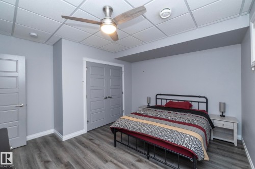 Spacious room featuring wood-finish flooring, a contemporary ceiling fan with integrated lighting, and a drop ceiling - 151 Caledonia Drive, Leduc, AB - Indoor Photo Showing Bedroom