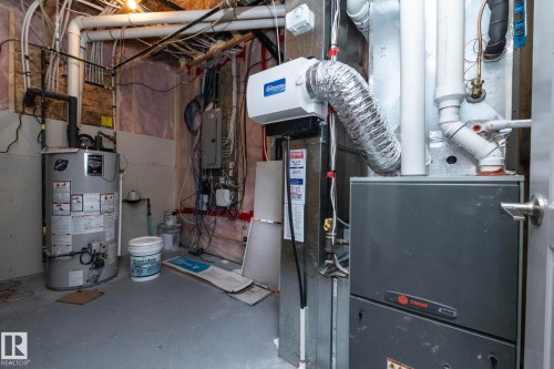 Utility room featuring a water heater, furnace, and exposed overhead piping - 151 Caledonia Drive, Leduc, AB - Indoor Photo Showing Basement