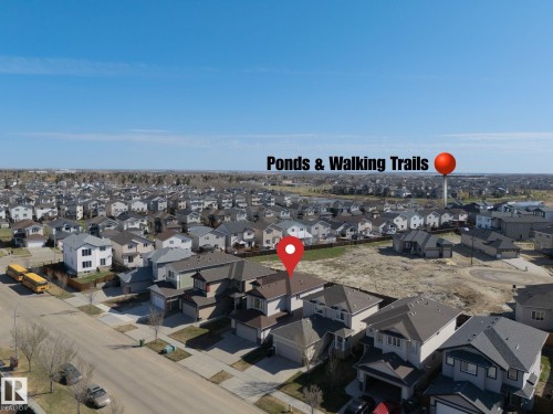 Aerial view showcasing a residential neighborhood with detached homes, clear blue skies, and undeveloped land - 151 Caledonia Drive, Leduc, AB - Outdoor With View