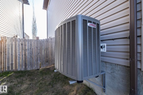 Exterior featuring a Lennox HVAC unit, light grey horizontal siding, brown downspout, and a wooden fence - 151 Caledonia Drive, Leduc, AB - Outdoor