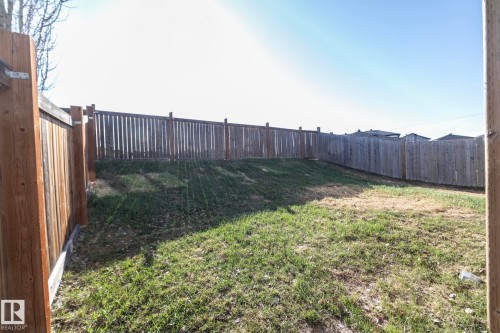 Expansive fenced backyard featuring a sloped grade and natural grass - 151 Caledonia Drive, Leduc, AB - Outdoor