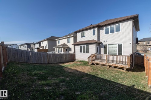 Rear exterior featuring light-colored siding, a brown shingle roof, and multiple windows - 151 Caledonia Drive, Leduc, AB - Outdoor