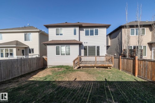 Rear exterior featuring a wood deck, fenced perimeter, multiple windows, and a sliding glass door - 151 Caledonia Drive, Leduc, AB - Outdoor