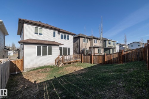 Expansive backyard featuring a partial grass lawn, full perimeter wood fencing, and a multi-level wood deck with stairs leading to the yard - 151 Caledonia Drive, Leduc, AB - Outdoor