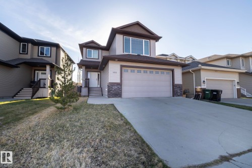 Two-story contemporary residence featuring a neutral siding exterior, stone veneer accents, and a prominent front-facing garage - 151 Caledonia Drive, Leduc, AB - Outdoor With Facade
