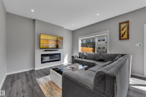 Living area featuring wood-finish flooring, recessed lighting, and a linear electric fireplace - 319 36 Avenue, Edmonton, AB - Indoor Photo Showing Living Room With Fireplace