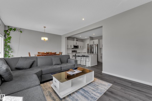 Open-concept living space featuring wood-finish flooring, recessed lighting, and a modern kitchen with a large island and stainless steel appliances - 319 36 Avenue, Edmonton, AB - Indoor Photo Showing Living Room