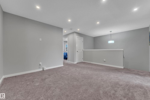 Spacious carpeted area featuring recessed lighting, a contemporary pendant light, and a white balustrade - 319 36 Avenue, Edmonton, AB - Indoor Photo Showing Other Room