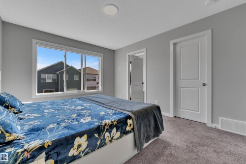 Bedroom featuring light gray walls, plush gray carpet, a wide window, white trim, and a white interior door - 319 36 Avenue, Edmonton, AB - Indoor Photo Showing Bedroom