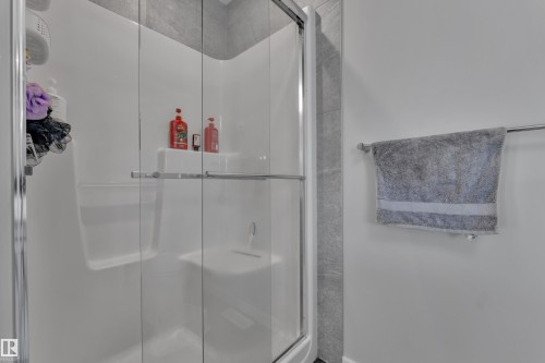 Shower enclosure featuring clear glass sliding doors and a white surround - 319 36 Avenue, Edmonton, AB - Indoor Photo Showing Bathroom