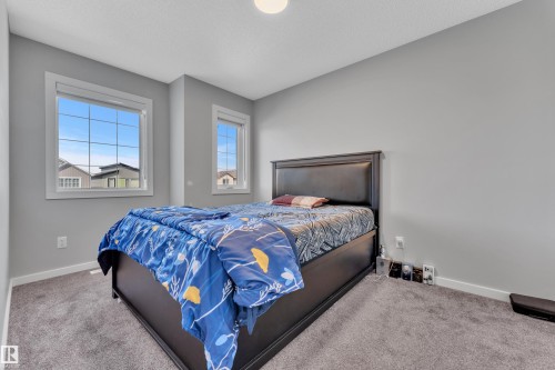Bedroom featuring light gray wall paint, gray carpet flooring, white baseboards, and two windows with white trim - 319 36 Avenue, Edmonton, AB - Indoor Photo Showing Bedroom
