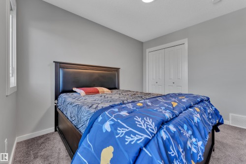 Carpeted room featuring light gray walls, a window with white trim, and a built-in closet with bi-fold doors - 319 36 Avenue, Edmonton, AB - Indoor Photo Showing Bedroom