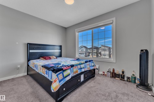 Bedroom featuring a large window, neutral gray wall tones, light gray carpeting, and a ceiling-mounted light fixture - 319 36 Avenue, Edmonton, AB - Indoor Photo Showing Bedroom
