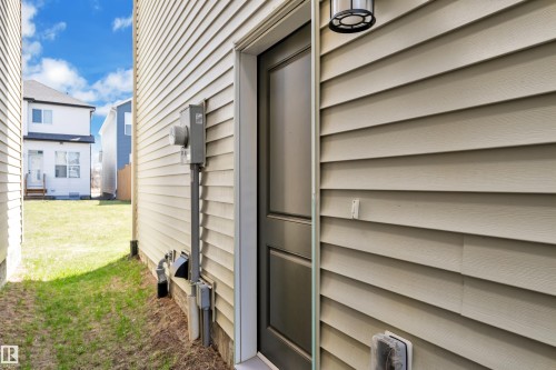 Exterior wall featuring horizontal siding, dark paneled door, and a wall-mounted outdoor light fixture - 319 36 Avenue, Edmonton, AB - Outdoor