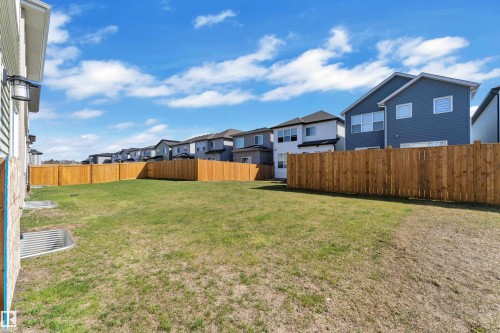 Expansive backyard featuring a green lawn, complete perimeter fencing, and a contemporary exterior light fixture - 319 36 Avenue, Edmonton, AB - Outdoor