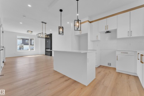 Bright open-concept living area featuring light wood-finish flooring, recessed lighting, and a contemporary kitchen with white cabinetry - 173 Graybriar Drive, Stony Plain, AB - Indoor Photo Showing Kitchen