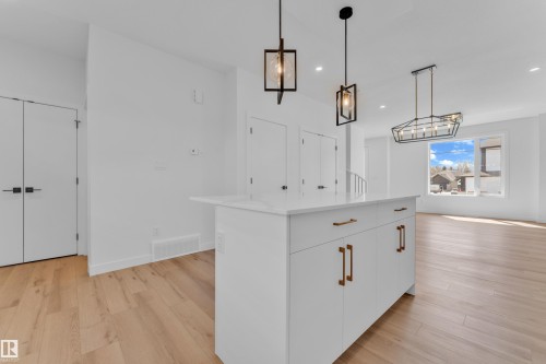 Kitchen island with white cabinetry, gold-toned hardware, and a light-toned countertop - 173 Graybriar Drive, Stony Plain, AB - Indoor Photo Showing Other Room