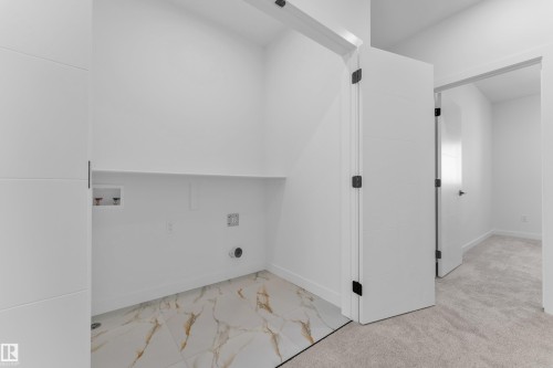 Dedicated laundry area featuring white and gold veined floor tiling, a utility shelf, and hook-ups for a washing machine and dryer - 173 Graybriar Drive, Stony Plain, AB - Indoor Photo Showing Other Room
