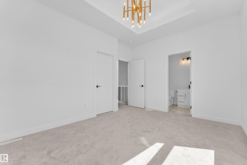 Carpeted room with a contemporary chandelier, tray ceiling, and white trim - 173 Graybriar Drive, Stony Plain, AB - Indoor Photo Showing Other Room