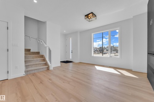 Open concept living area featuring light wood-finish flooring, a contemporary flush mount light fixture, and a large window - 173 Graybriar Drive, Stony Plain, AB - Indoor Photo Showing Other Room