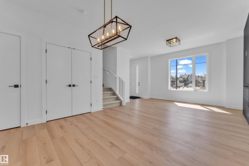Spacious entry area with light wood-finish flooring, white walls, and a contemporary chandelier - 173 Graybriar Drive, Stony Plain, AB - Indoor Photo Showing Other Room