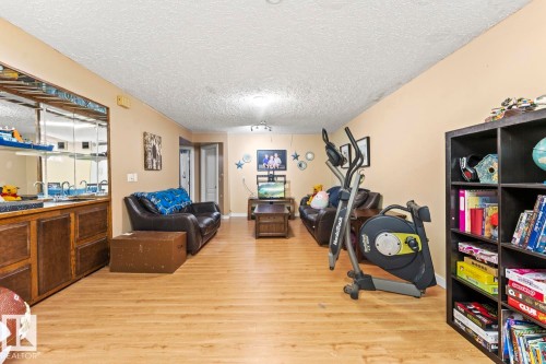 Spacious room featuring wood-finish flooring, a built-in wet bar with mirrored backsplash, and recessed lighting - 4908 59 Street, Cold Lake, AB - Indoor