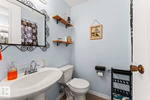 Pedestal sink with chrome fixtures and a decorative black wrought iron mirror - 4908 59 Street, Cold Lake, AB - Indoor Photo Showing Bathroom