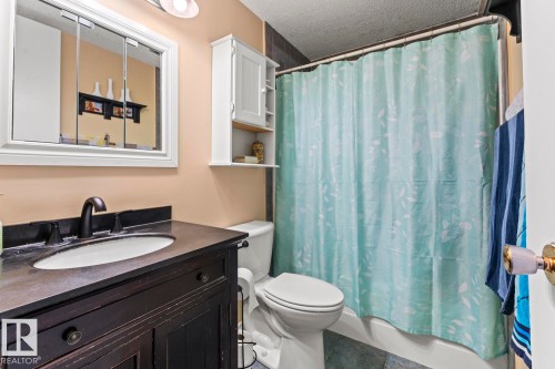 Bathroom featuring a dark wood vanity with an integrated sink and matte black faucet, a medicine cabinet, white wall-mounted storage, a toilet, and a shower-over-tub combination - 4908 59 Street, Cold Lake, AB - Indoor Photo Showing Bathroom