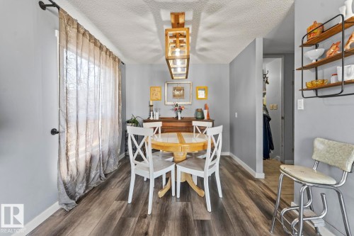 Dining area with wood-finish flooring, light gray walls, and a large window with sheer drapes - 4908 59 Street, Cold Lake, AB - Indoor Photo Showing Dining Room