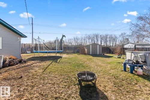 Spacious backyard featuring a fire pit, a storage shed, and an above-ground pool - 4908 59 Street, Cold Lake, AB - Outdoor