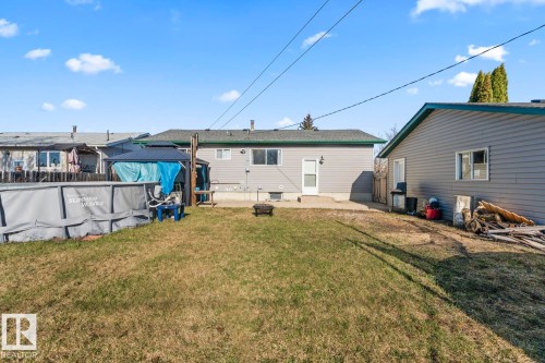 Expansive backyard featuring a manicured lawn, concrete patio, and a separate structure with siding - 4908 59 Street, Cold Lake, AB - Outdoor With Exterior