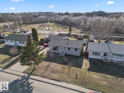 Light gray-sided residence featuring a dark gray shingle roof, white trim, and a white front porch - 4908 59 Street, Cold Lake, AB - Outdoor With View