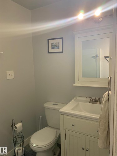 This bathroom features a white vanity with a single sink and a mirrored cabinet above - 5030 40 Street, Cold Lake, AB - Indoor Photo Showing Bathroom