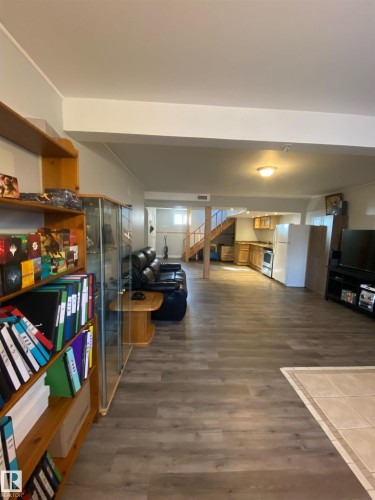 Spacious open-concept room featuring wood-look flooring, recessed lighting, and a visible staircase - 5030 40 Street, Cold Lake, AB - Indoor Photo Showing Other Room