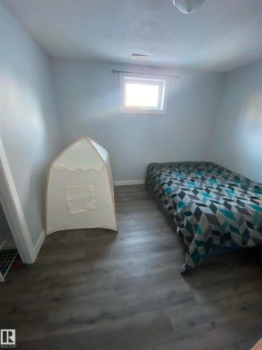 This room features light-toned walls, a window providing natural light, and durable plank flooring - 5030 40 Street, Cold Lake, AB - Indoor Photo Showing Bedroom