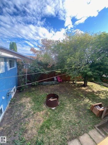The property features a fenced yard with mature trees and a fire pit, offering a private outdoor space - 5030 40 Street, Cold Lake, AB - Outdoor