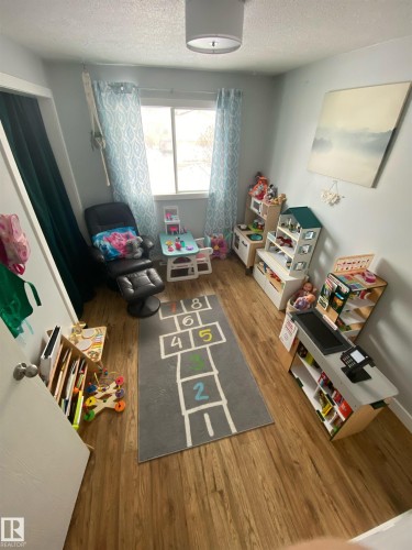 The room features wood-style flooring and a window with patterned curtains, providing natural light - 5030 40 Street, Cold Lake, AB - Indoor