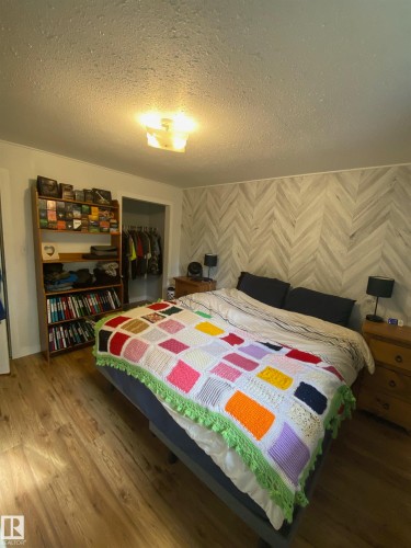 This room features hardwood flooring and a decorative accent wall with a chevron pattern - 5030 40 Street, Cold Lake, AB - Indoor Photo Showing Bedroom